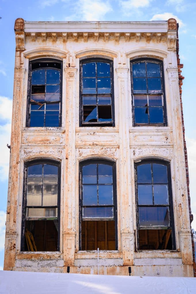Tall, weathered building with large windows against a blue sky