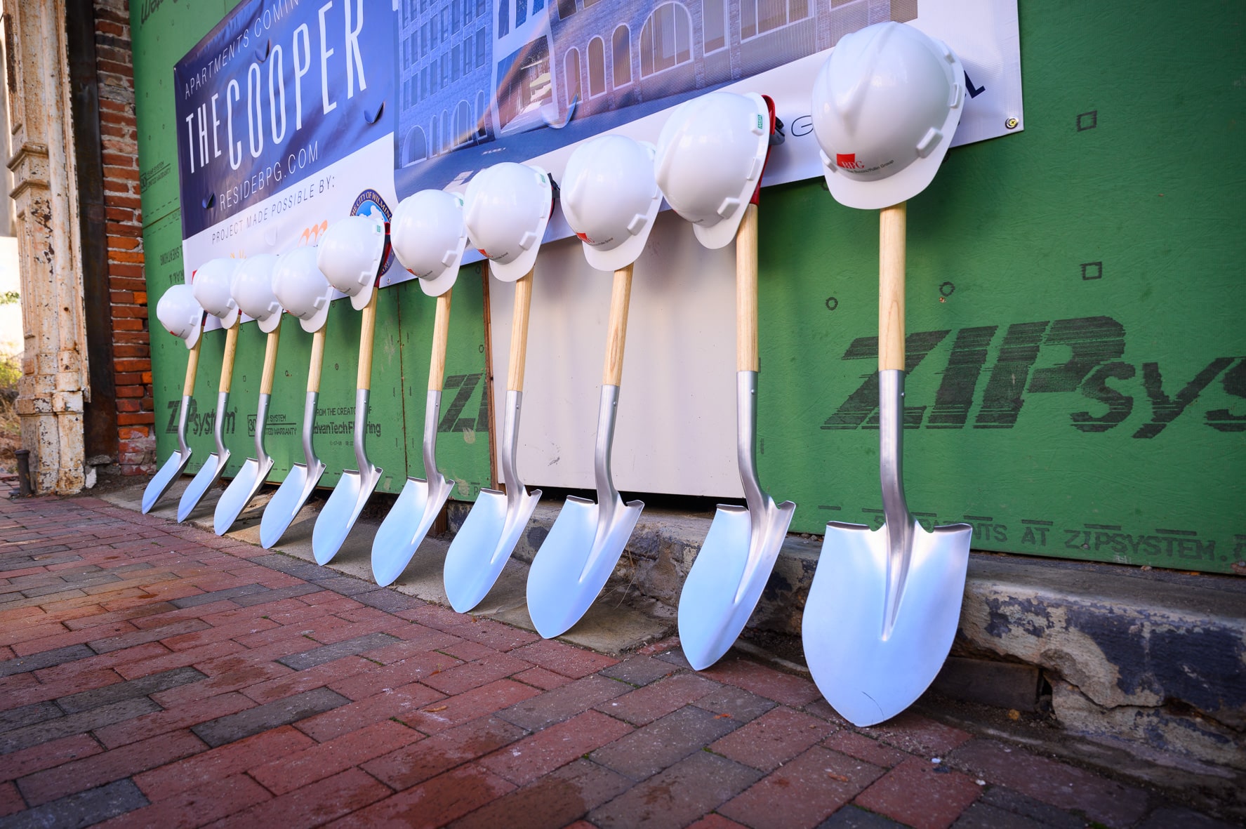 Hardhats leaning on shovels at The Cooper development site