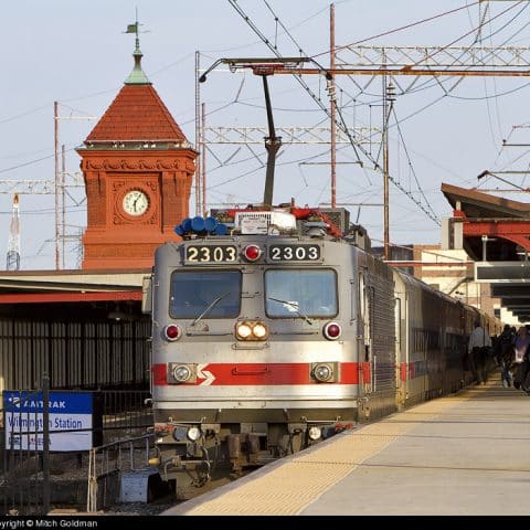 Amtrak train pulling in to station in Wilmington, DE with red clock tower in background